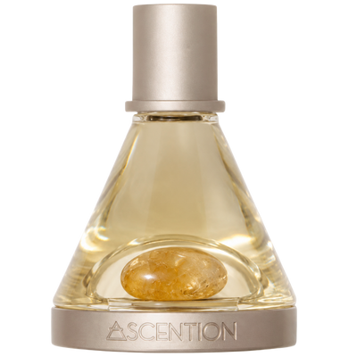 A bottle of Ascention fragrance with a clear glass body, pale golden liquid, a polished CITRINE stone inside, and a brushed silver cap and base. The brand name ASCENTION is engraved on the base.