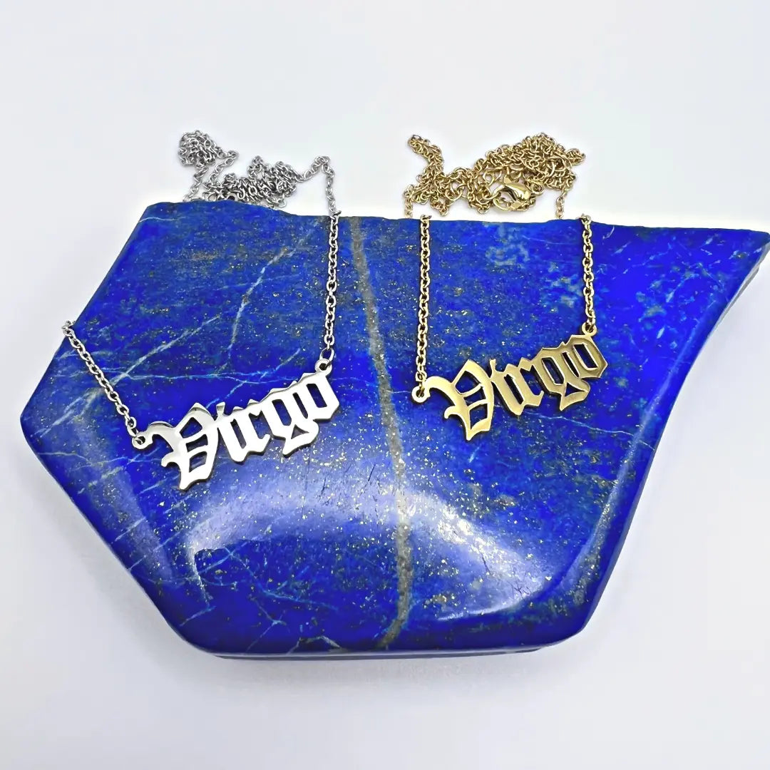 Ascention Beauty's Zodiac Necklaces, featuring Virgo pendants in both silver and gold tones, are beautifully showcased on a blue gemstone. The chains elegantly drape over the stone, capturing a celestial and cosmic essence.