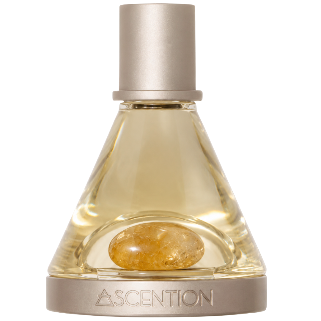 A bottle of Ascention fragrance with a clear glass body, pale golden liquid, a polished CITRINE stone inside, and a brushed silver cap and base. The brand name ASCENTION is engraved on the base.
